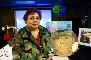 Wearing her son's military jacket, Gabriella Barajas holds a portrait of her son Army Veteran Gabriel Barajas created of sand, which will be displayed on the Donate Life's Rose Bowl parade float, during the celebration of his organ donation at the offices of the Nevada Donor Network Wednesday, December 19, 2012.